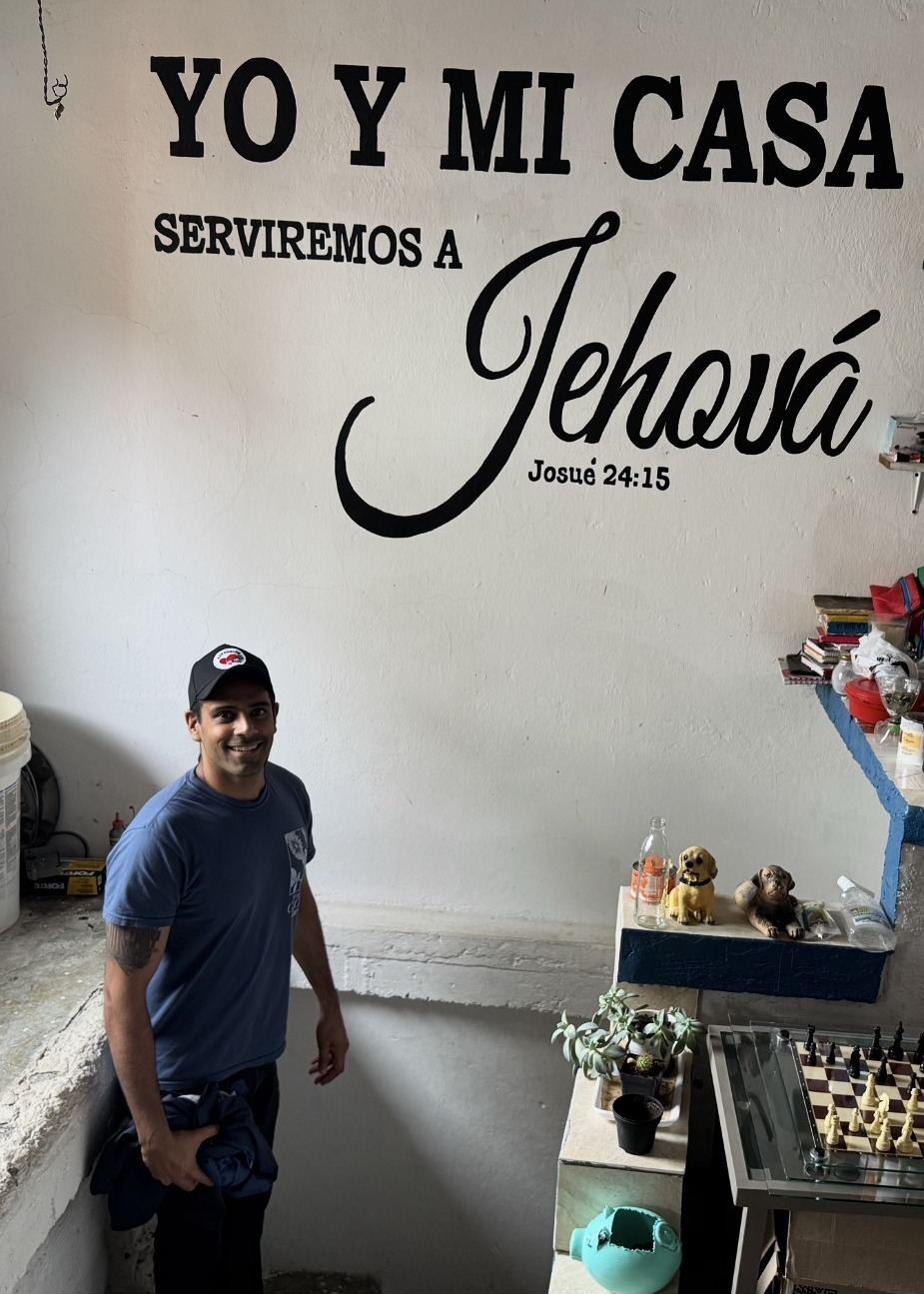 Rahul standing before a wall painted with Joshua 24:15 in Spanish &mdash; &ldquo;Yo y mi casa serviremos a Jehov&aacute;&rdquo; &mdash; As for me and my house, we will serve the LORD.